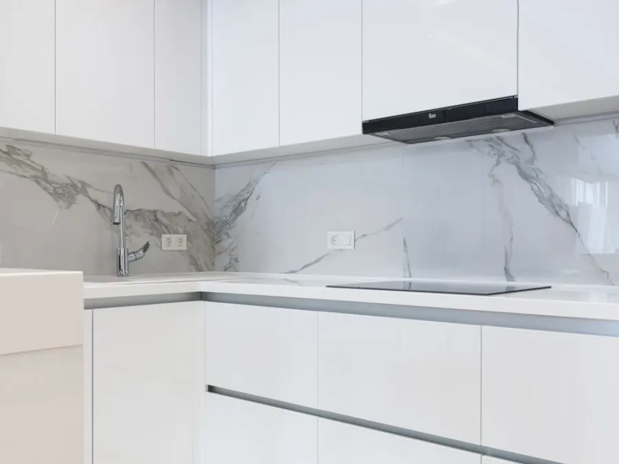 White kitchen cabinets above a marble-patterned countertop — illustrative stock photo